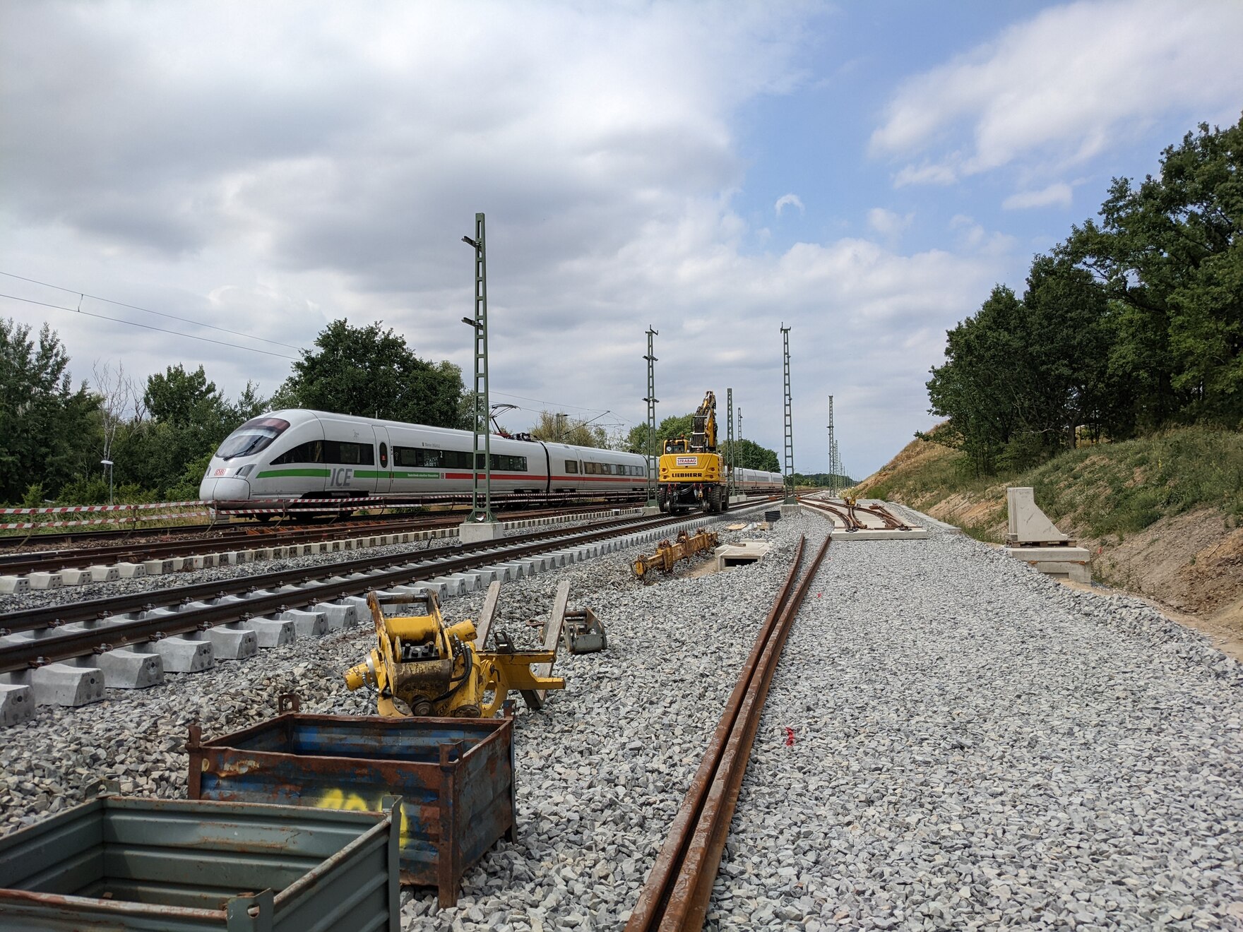 Baustelle neben einem ICE auf der Schiene.