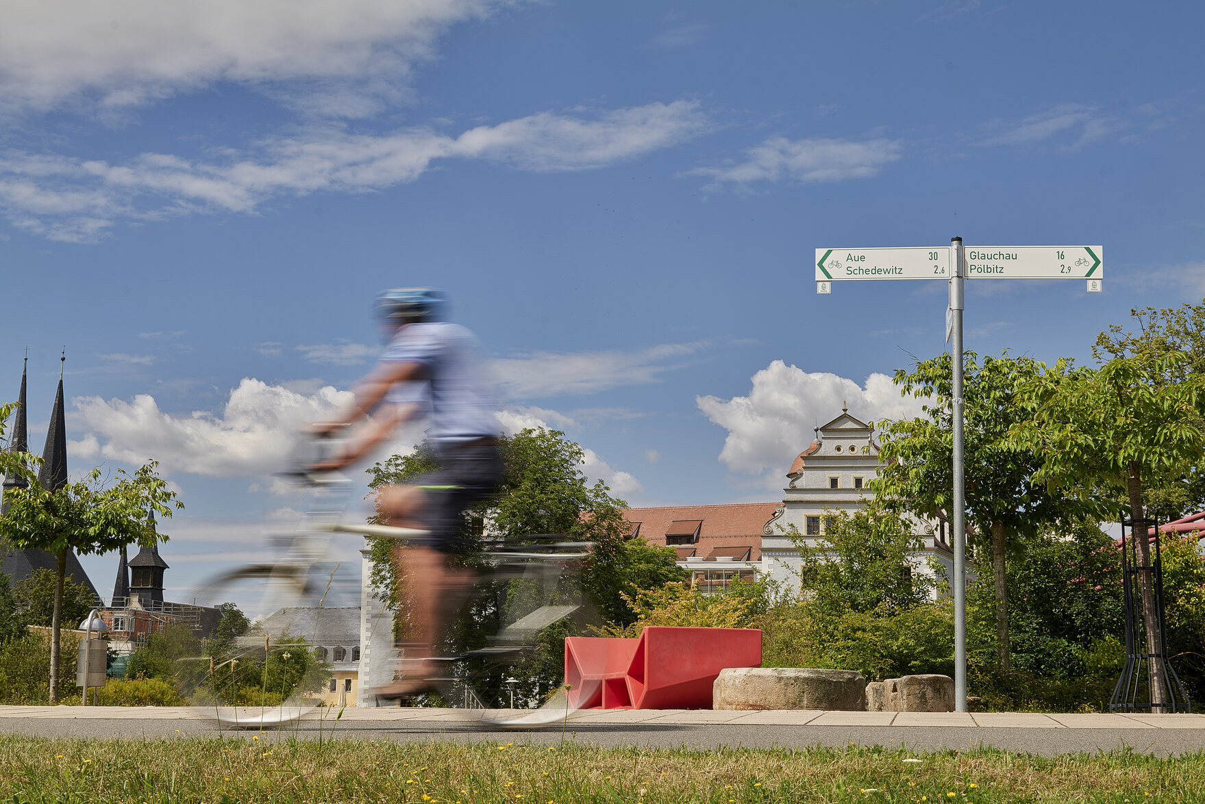 Mulderadweg mit einem Radfahrer im Vordergrund und Osterstein sowie Paradiesbrücke in Zwickau im Hintergrund