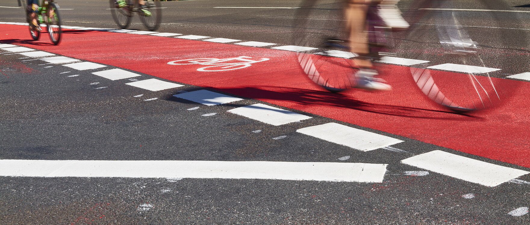 Drei Fahrradfahrer auf einem straßenbegleitenden Radweg.