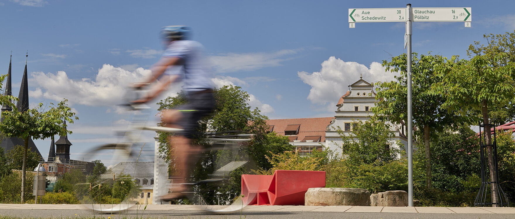 Mulderadweg mit einem Radfahrer im Vordergrund und Osterstein sowie Paradiesbrücke in Zwickau im Hintergrund