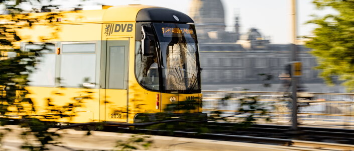 Eine gelbe Straßenbahn in der Fahrt. 